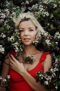 Portrait of beautiful woman standing by flowering plants