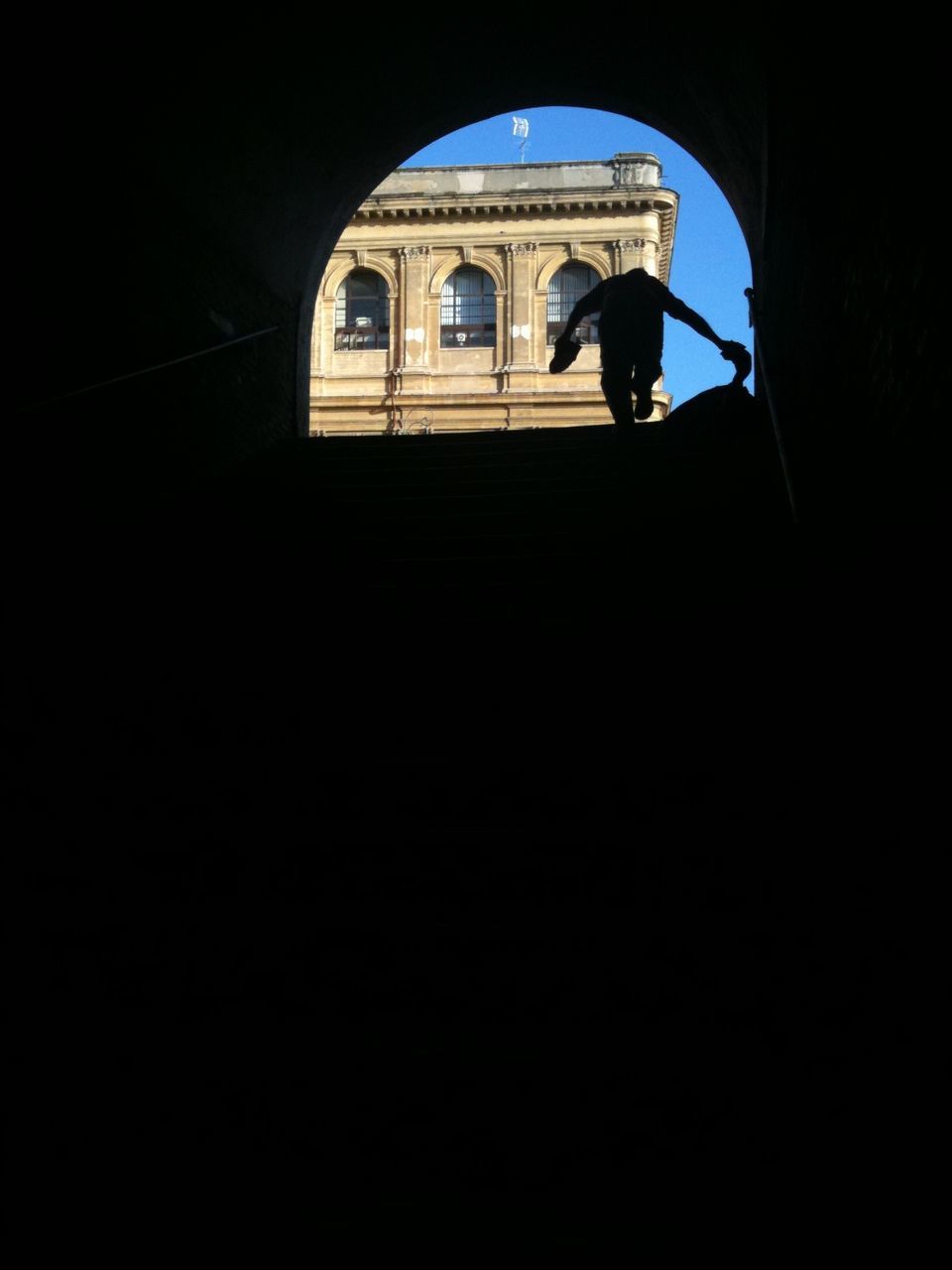 architecture, arch, indoors, built structure, lifestyles, window, silhouette, men, steps, full length, tunnel, dark, archway, standing, walking, low angle view, person, rear view