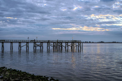 Pier over sea against sky during sunset