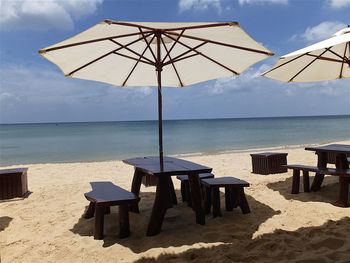 Chairs and table on beach against sky