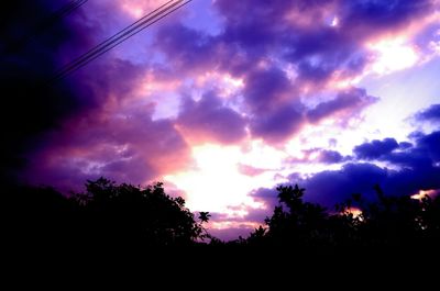 Low angle view of silhouette trees against dramatic sky