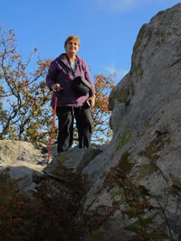 Low angle view of woman standing by rock formation against sky