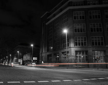 Illuminated road against buildings at night