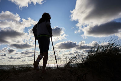 Rear view of silhouette man standing on beach against sky