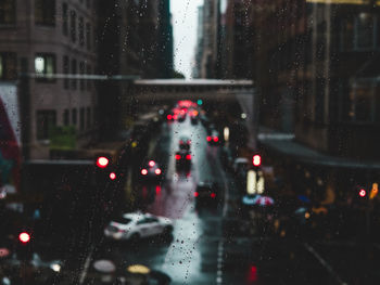 Cars on city street seen through wet glass window