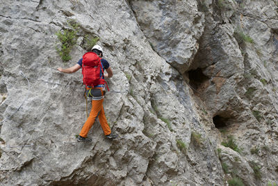 Full length of backpacker walking on metal mounted on rock formation