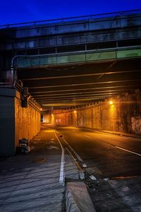 Illuminated street amidst buildings in city at night