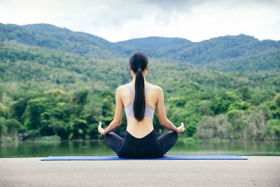 Rear view of woman with arms raised against plants