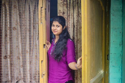 Portrait of young woman standing at doorway