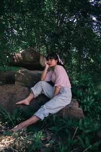 Side view of woman sitting on land