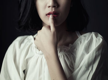 Close-up of young woman looking away against black background