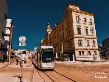 Cars on street by buildings in city against sky