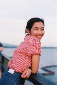 Young woman sitting on beach against sky