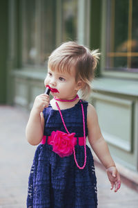 Adorable baby in a dress paints lips with lipstick