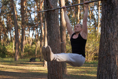 Full length of man exercising at forest