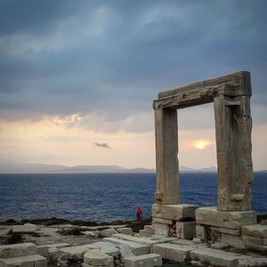 Old ruins on sea against sky during sunset