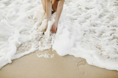 Low section of woman standing on shore at beach