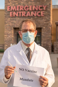 Portrait of doctor wearing mask holding paper with text