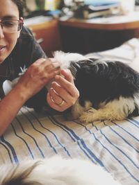 Midsection of woman with dog relaxing on bed