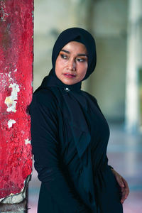 Beautiful indonesian woman wearing a black hijab against the rustic wall as a background