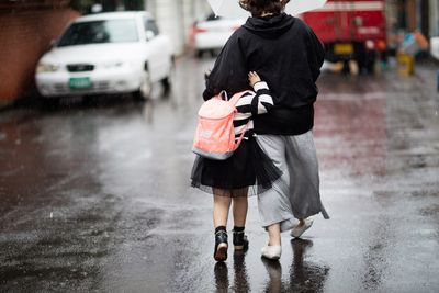 Rear view of mother and daughter walking on wet street