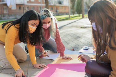 Females wearing mask writing on posters on street