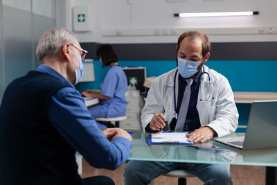 Doctor wearing mask examining patient in clinic