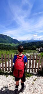 Rear view of boy on mountain against sky