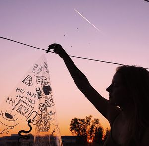 Low angle view of silhouette woman holding umbrella against sky during sunset