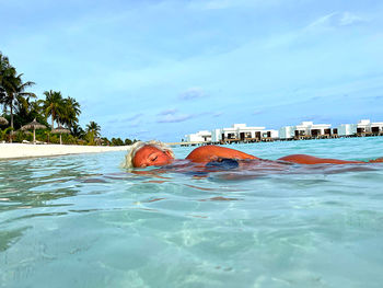 Man swimming in pool by sea against sky