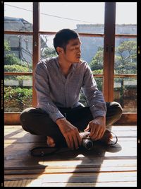 Young man looking down while sitting on floor