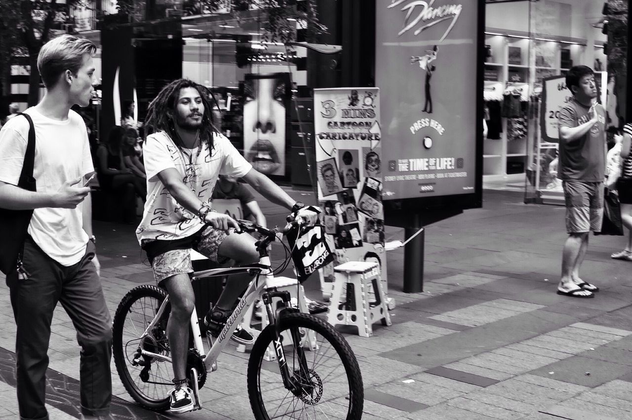 bicycle, transportation, street, mode of transport, land vehicle, lifestyles, full length, men, casual clothing, leisure activity, city, building exterior, riding, city life, road, architecture, walking, built structure