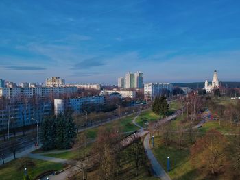 High angle view of trees and buildings against blue sky