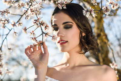 Young woman smelling almond flower blossom