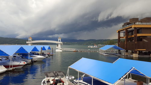 Boats in harbor against cloudy sky