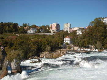 Scenic view of river by trees against clear blue sky