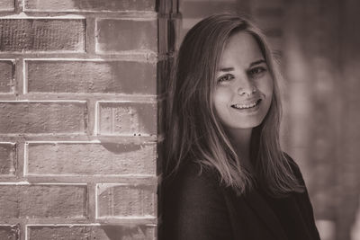 Portrait of smiling beautiful woman standing by architectural column