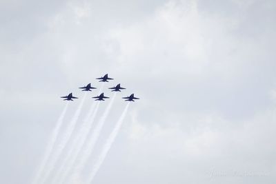 Low angle view of airshow against cloudy sky