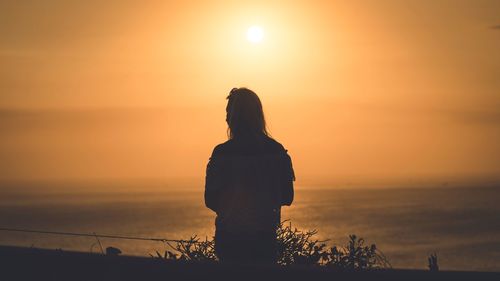 Silhouette woman looking at sunset