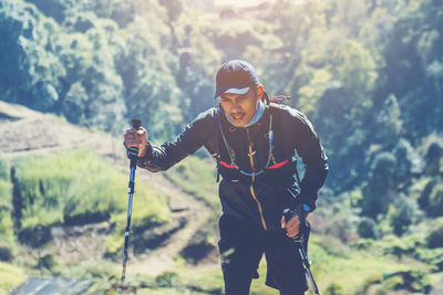 Young man standing against trees in forest