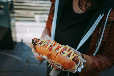 Midsection of man holding hot dog