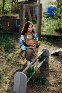 Young woman holding bowl in farm