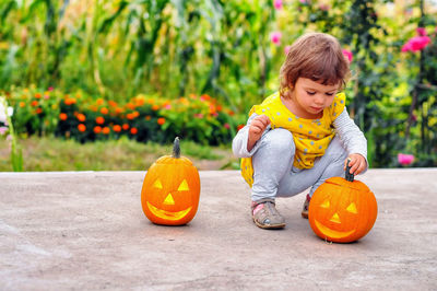 Portrait of cute smiling boy standing by pumpkin during autumn