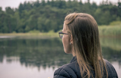 Rear view of woman standing by lake