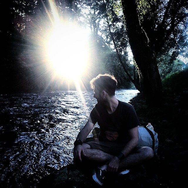 lifestyles, leisure activity, tree, sitting, sunlight, casual clothing, sun, water, sunbeam, person, childhood, three quarter length, full length, relaxation, lens flare, lake, rear view, nature