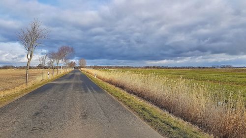 Road amidst field against sky