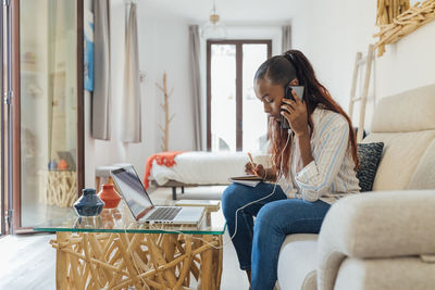 Man using mobile phone while sitting on sofa at home