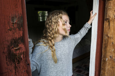 Blond girl passing wooden door