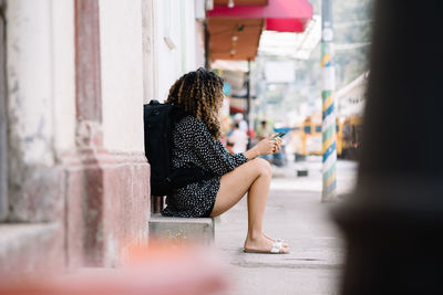 Side view of woman sitting on street