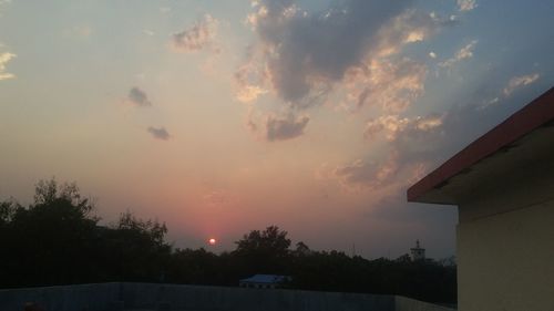 Low angle view of silhouette trees and buildings against sky during sunset